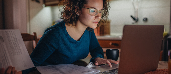 Person reviewing paper bills and using a laptop