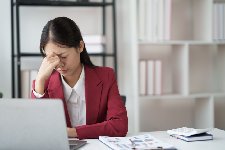 Asian businesswoman feeling stressed while doing paperwork in office